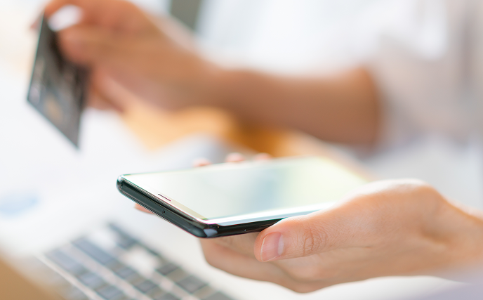 Hands holding credit card and using laptop and mobile phone for online shopping